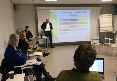 Scherm, spreker en mensen in de zaal