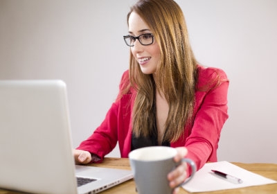Dame met een kop koffie achter de laptop